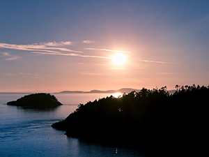 Scenic photo of the sun rising above islands and land masses in Puget Sound